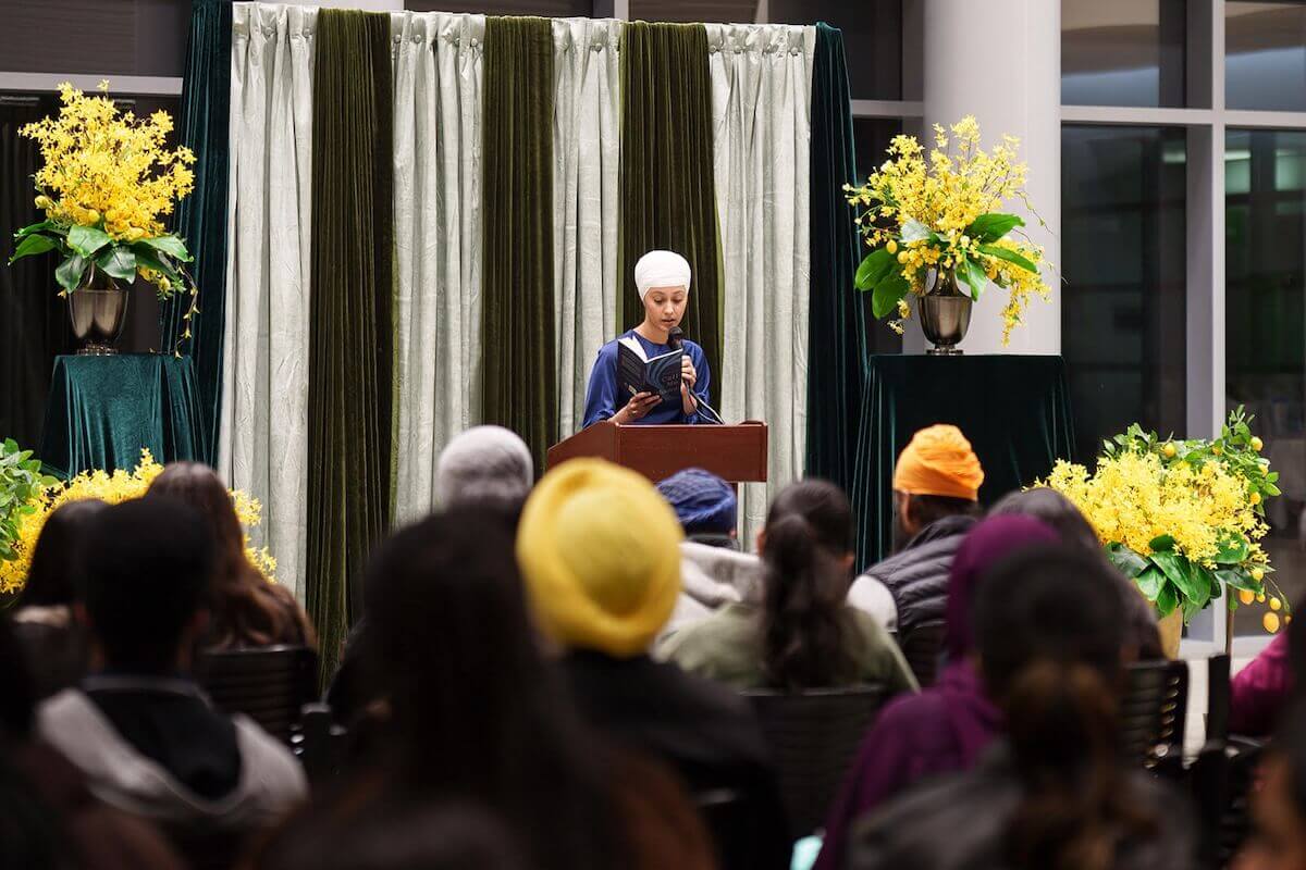 Harman Kaur at a poetry reading on stage with an audience
